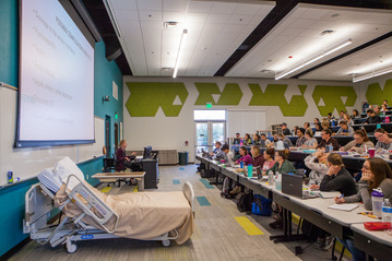 Instruction in the stacked seated lecture hall with students.